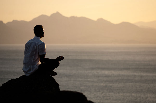 Man Sitting On Rock Overlooking Water Reflect